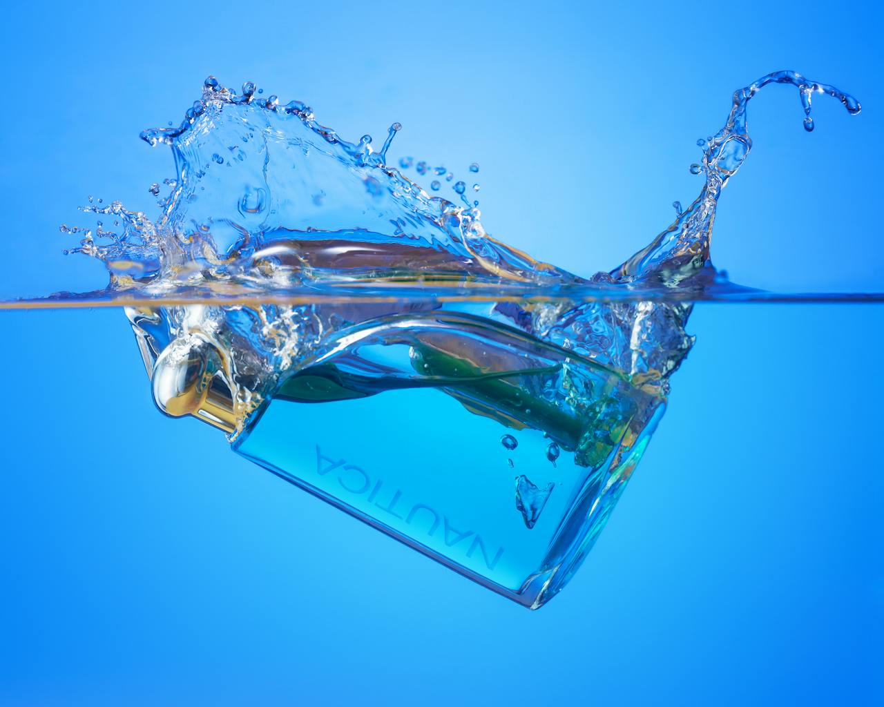 about-us Captivating image of a perfume bottle creating a dynamic splash effect in water.